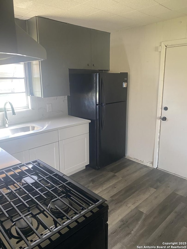 kitchen featuring dark hardwood / wood-style floors, white cabinetry, sink, black appliances, and wall chimney exhaust hood