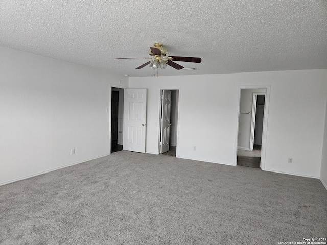 empty room featuring ceiling fan, dark carpet, and a textured ceiling