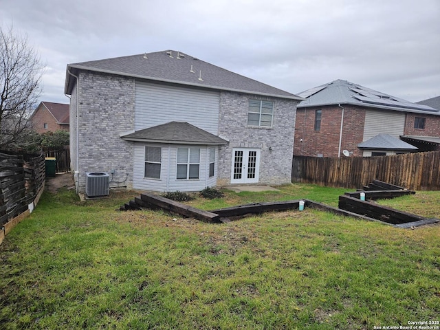 rear view of house with french doors, central AC, and a lawn