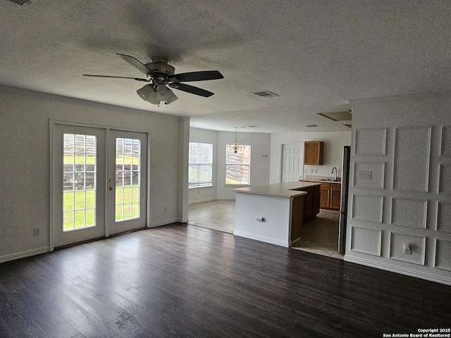 unfurnished living room featuring sink, ceiling fan, a textured ceiling, dark hardwood / wood-style flooring, and french doors