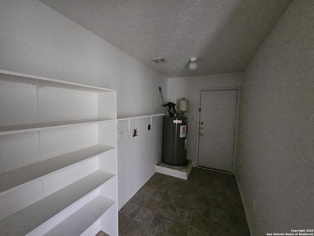 clothes washing area featuring electric water heater and a textured ceiling