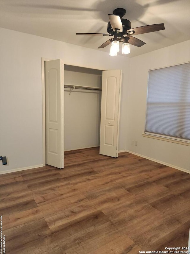 unfurnished bedroom featuring dark wood-type flooring, ceiling fan, and a closet