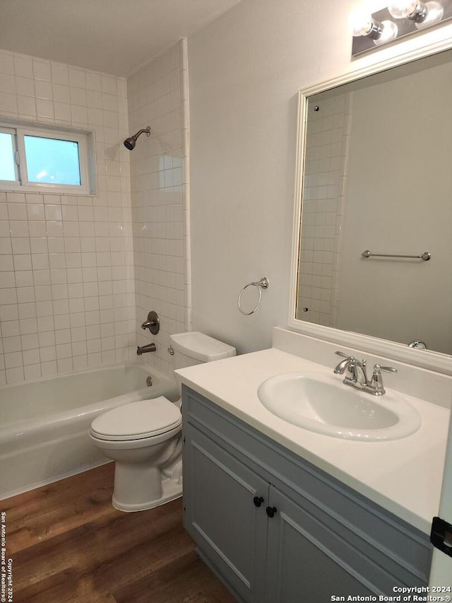 full bathroom with vanity, tiled shower / bath combo, wood-type flooring, and toilet