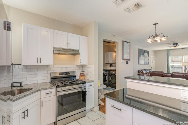 kitchen with tasteful backsplash, sink, white cabinets, stainless steel gas range, and washer and clothes dryer