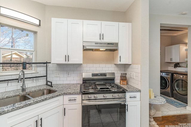 kitchen with white cabinetry, sink, washing machine and clothes dryer, light stone countertops, and stainless steel gas range