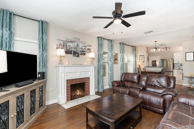 living room featuring ceiling fan with notable chandelier, a fireplace, and dark hardwood / wood-style flooring