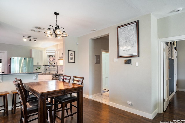 dining area with dark wood-type flooring, a chandelier, and sink