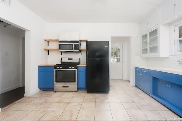 kitchen featuring light tile patterned flooring, blue cabinets, sink, appliances with stainless steel finishes, and white cabinets