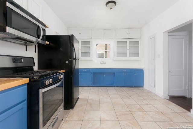 kitchen featuring stainless steel appliances, white cabinetry, blue cabinets, and light tile patterned floors