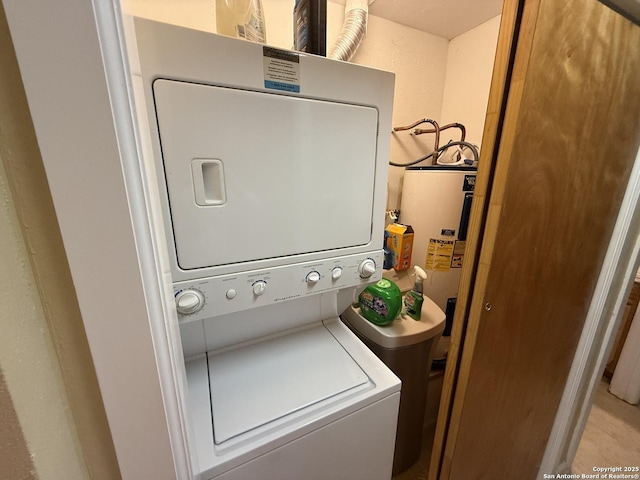 clothes washing area with stacked washer / drying machine and water heater