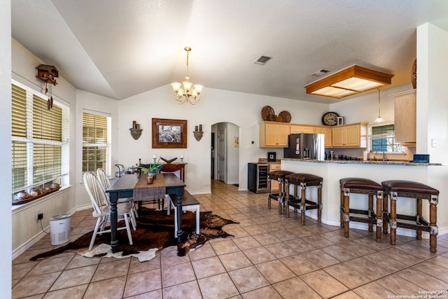 tiled dining room featuring an inviting chandelier and vaulted ceiling