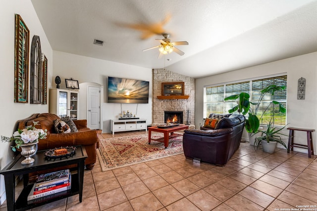 tiled living room featuring ceiling fan, lofted ceiling, a textured ceiling, and a fireplace