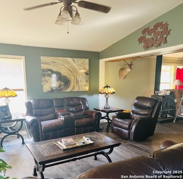 living room with lofted ceiling, hardwood / wood-style floors, ceiling fan, and a wood stove