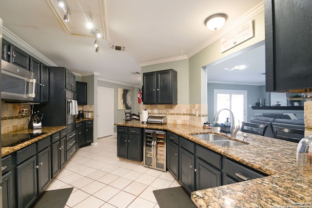 kitchen with sink, stone counters, appliances with stainless steel finishes, wine cooler, and kitchen peninsula