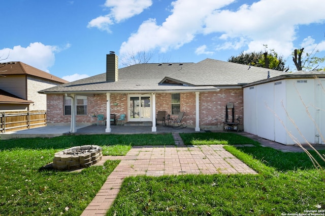 back of property with an outdoor fire pit, a yard, and a patio