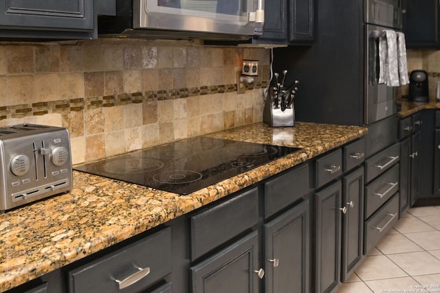 kitchen featuring light tile patterned flooring, black electric stovetop, decorative backsplash, and stone counters