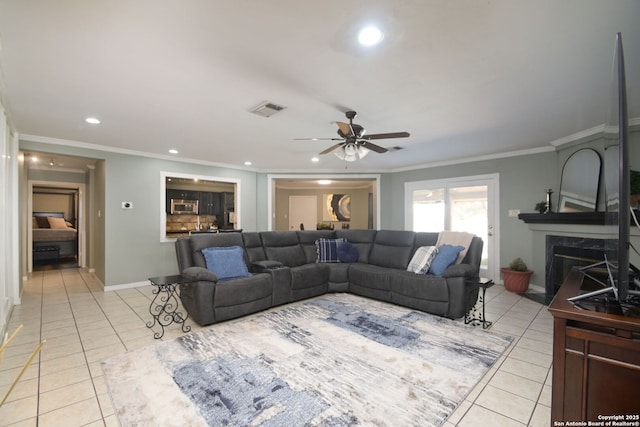 living room with crown molding, light tile patterned floors, ceiling fan, and a fireplace