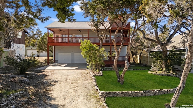 view of front of house with a garage, a front yard, ceiling fan, and a balcony