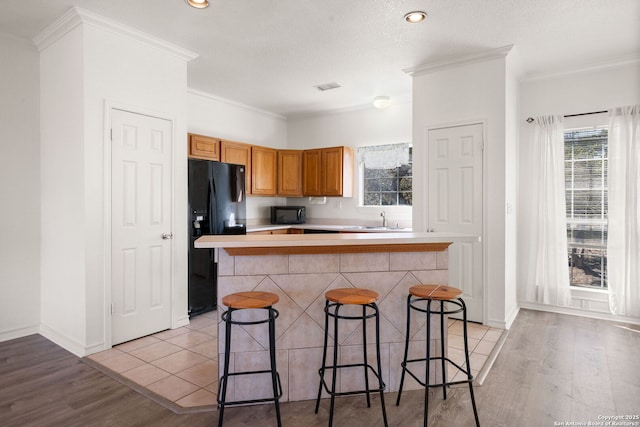 kitchen featuring a center island, sink, a breakfast bar, and black appliances