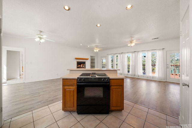 kitchen featuring ceiling fan, light tile patterned floors, a textured ceiling, and black range with electric cooktop