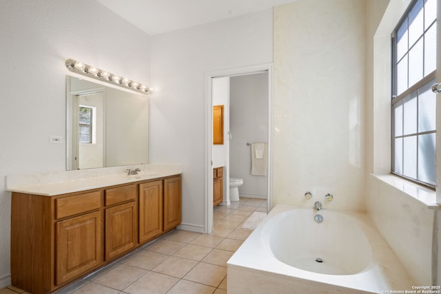 bathroom featuring tile patterned flooring, a bath, vanity, and toilet