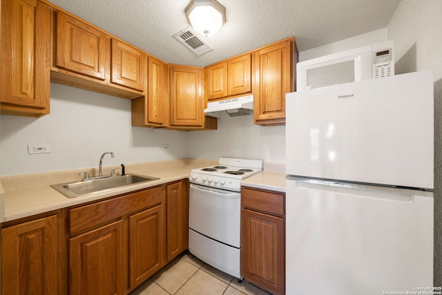 kitchen with light tile patterned flooring, sink, a textured ceiling, and white appliances