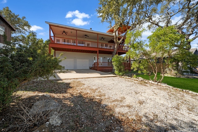 rear view of property featuring a garage, a balcony, and ceiling fan