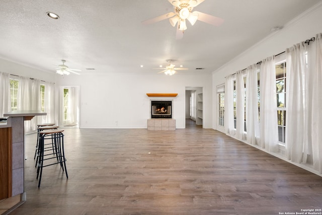 unfurnished living room with hardwood / wood-style floors, a wealth of natural light, a fireplace, and a textured ceiling