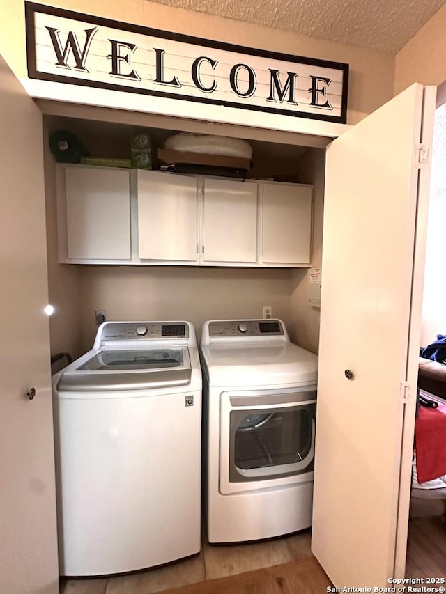 laundry room featuring independent washer and dryer, hardwood / wood-style flooring, cabinets, and a textured ceiling