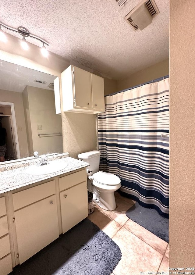 bathroom featuring tile patterned floors, toilet, rail lighting, a textured ceiling, and vanity