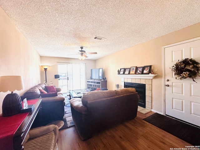 living room with hardwood / wood-style flooring, a fireplace, a textured ceiling, and ceiling fan