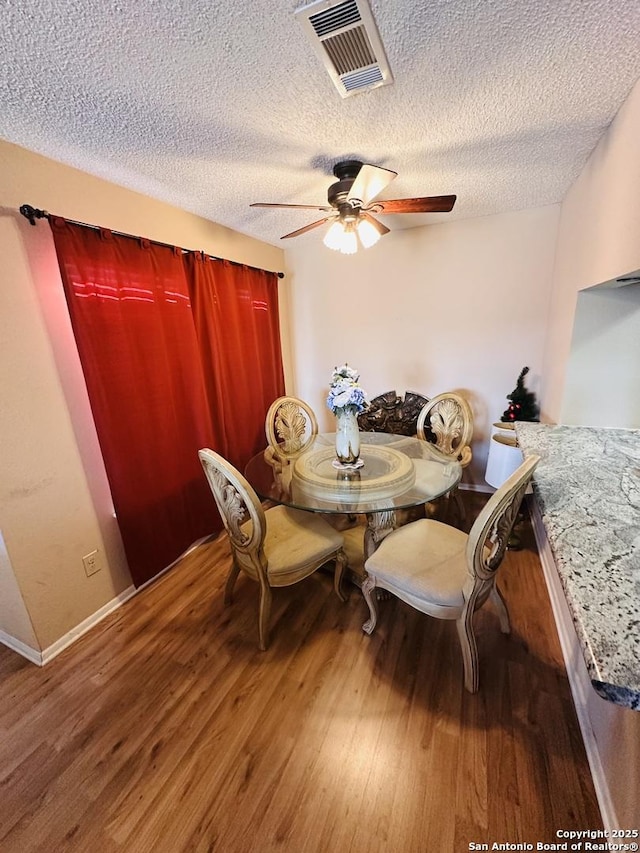 dining area featuring hardwood / wood-style flooring, ceiling fan, and a textured ceiling