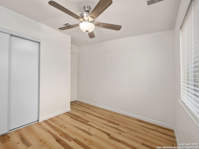 unfurnished bedroom featuring ceiling fan, a closet, light hardwood / wood-style floors, and multiple windows