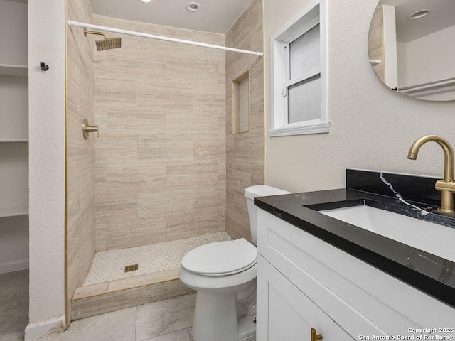 bathroom with vanity, toilet, and a tile shower