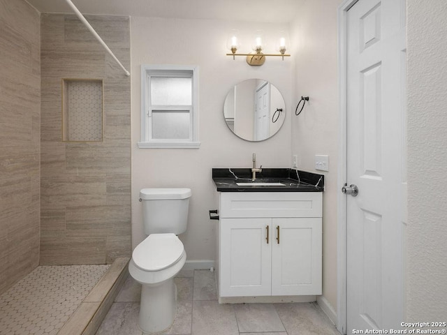 bathroom with vanity, tiled shower, and toilet