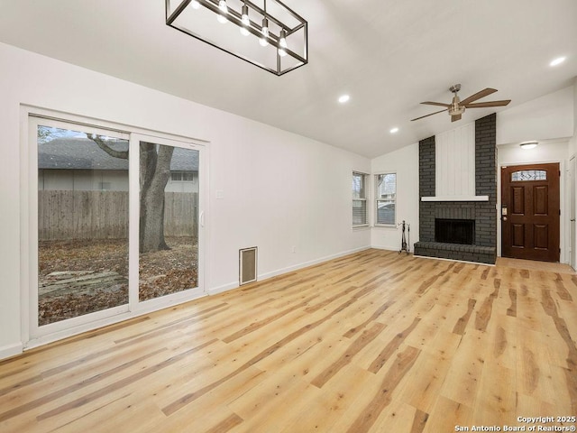 unfurnished living room with ceiling fan, lofted ceiling, a fireplace, and light hardwood / wood-style floors