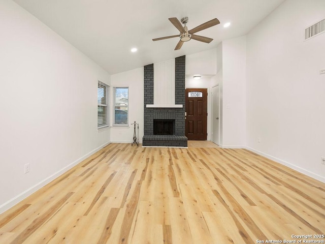 unfurnished living room with a brick fireplace, vaulted ceiling, light hardwood / wood-style floors, and ceiling fan