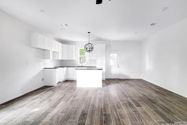 kitchen with pendant lighting, sink, white cabinetry, a center island, and light wood-type flooring