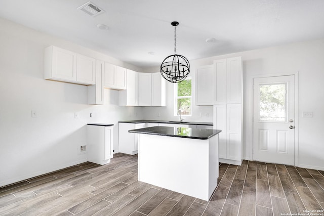 kitchen with sink, white cabinetry, hanging light fixtures, a kitchen island, and a chandelier