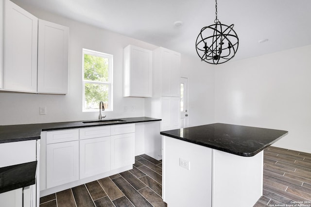 kitchen with white cabinetry, decorative light fixtures, sink, and a kitchen island