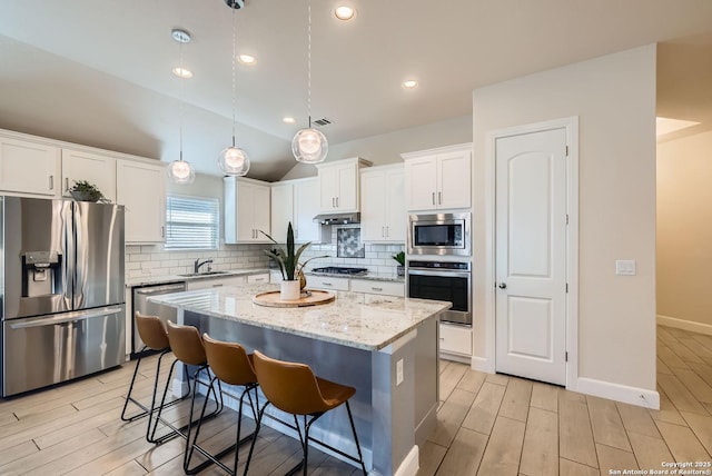 kitchen with white cabinetry, tasteful backsplash, decorative light fixtures, appliances with stainless steel finishes, and a kitchen island