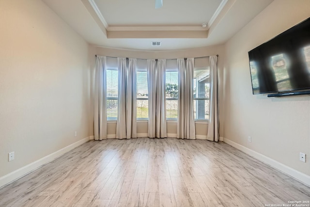 spare room with ornamental molding, a raised ceiling, and light hardwood / wood-style flooring