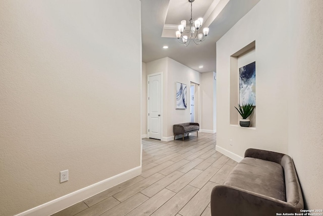 hall featuring an inviting chandelier and a tray ceiling