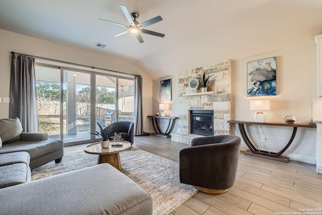 living room with vaulted ceiling, light wood-type flooring, ceiling fan, and a fireplace