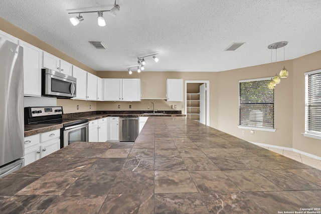 kitchen with sink, white cabinetry, decorative light fixtures, a textured ceiling, and appliances with stainless steel finishes