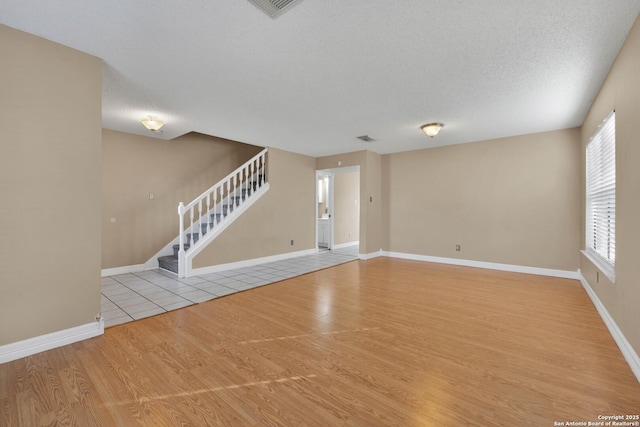 unfurnished living room with a textured ceiling and light wood-type flooring