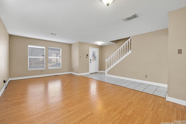 entrance foyer with a textured ceiling and light hardwood / wood-style floors