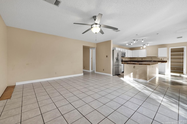 unfurnished living room featuring sink, light tile patterned floors, a textured ceiling, and ceiling fan