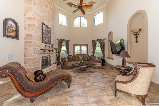 living room featuring crown molding, ceiling fan, plenty of natural light, and a brick fireplace