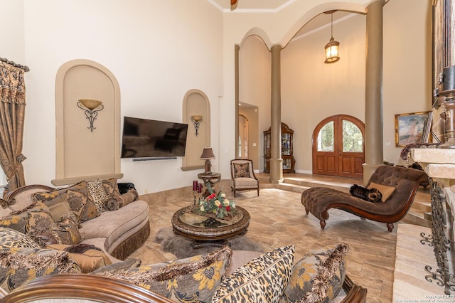 living room with a towering ceiling, ornamental molding, and ornate columns